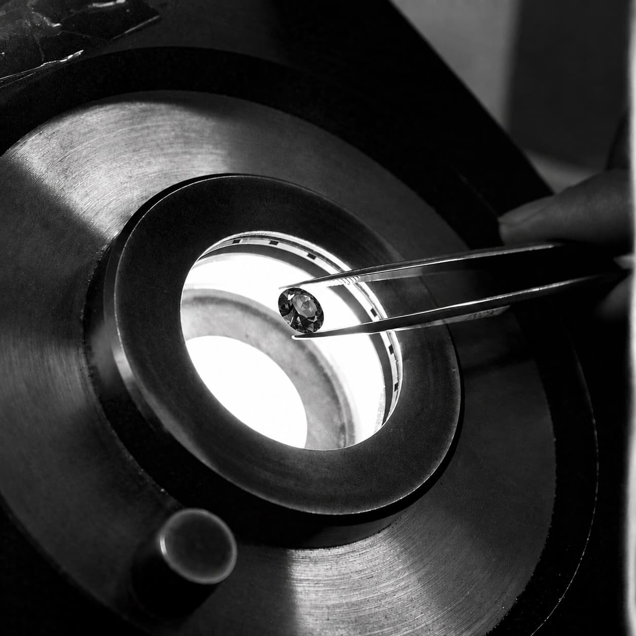 A gemstone held in tweezers over the light.